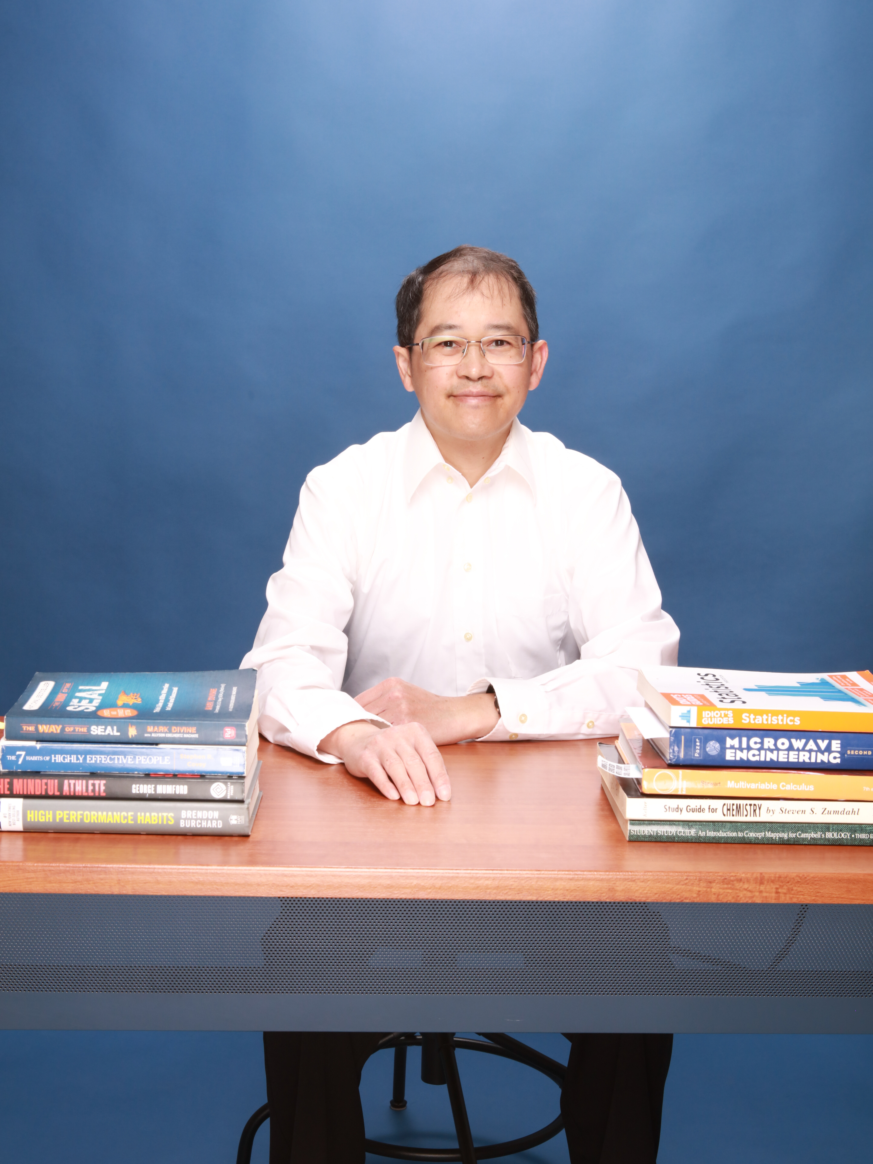 Henry Nguyen sitting up and showing some books used in tutoring and helping students succeed.